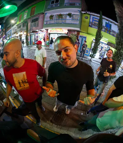 A group of men posing on a cobblestone street at night, with brightly colored colonial buildings in the background.